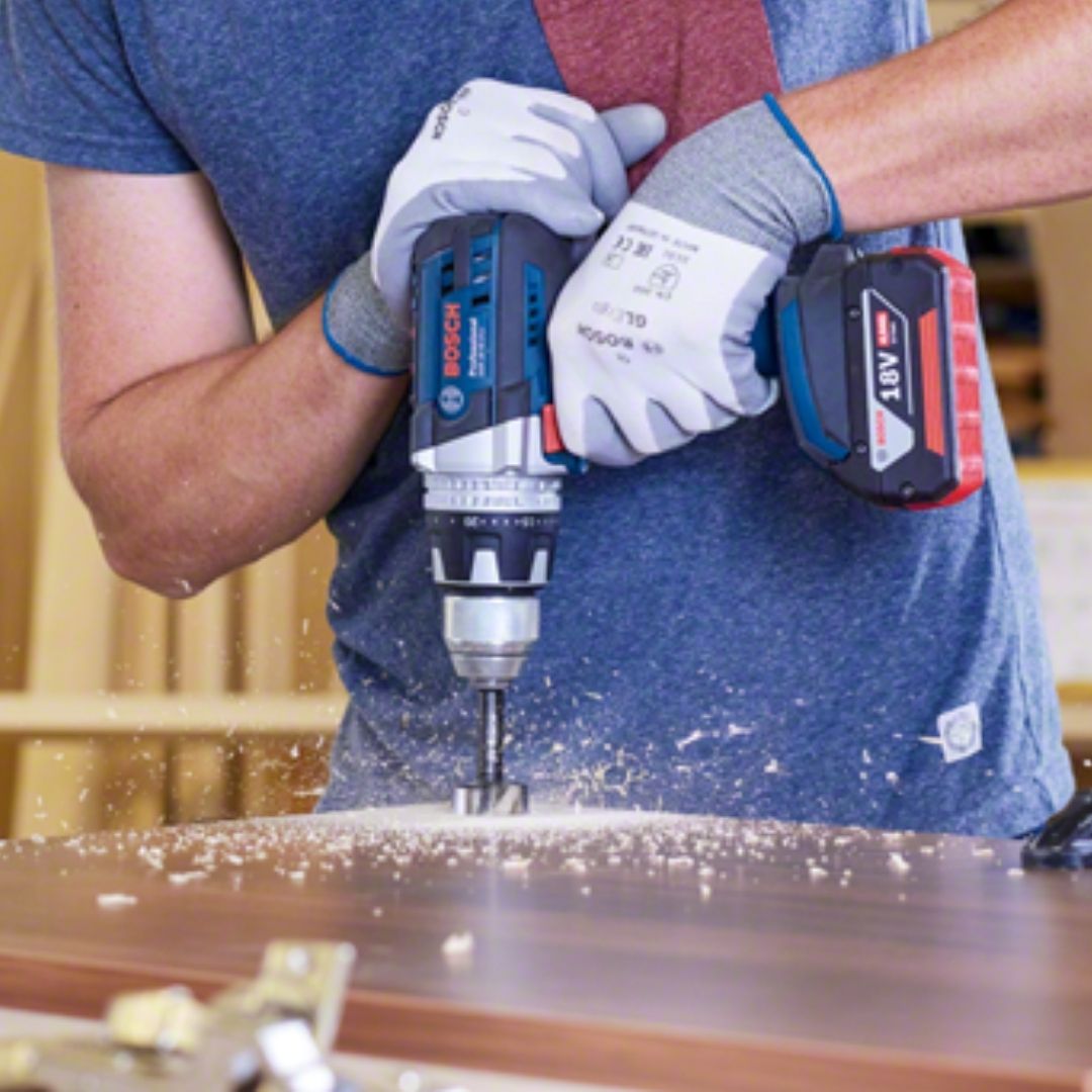 Person using a Bosch power drill on a wooden surface